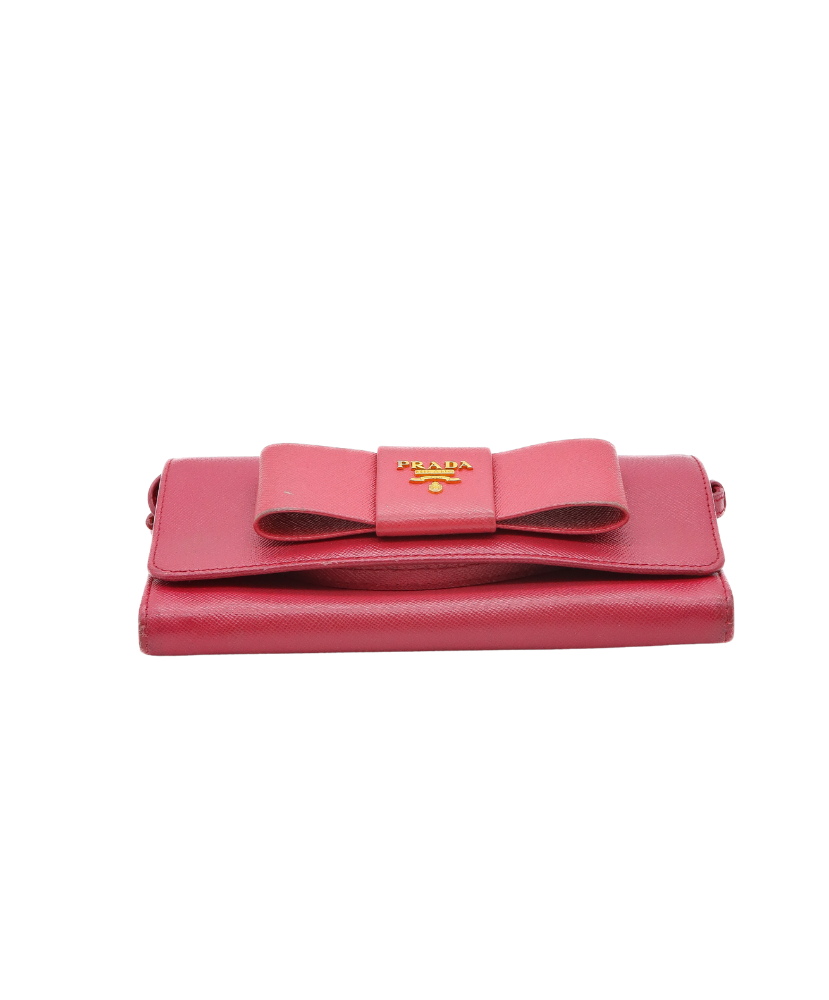 Pink prada wallet with a large bow on a white background