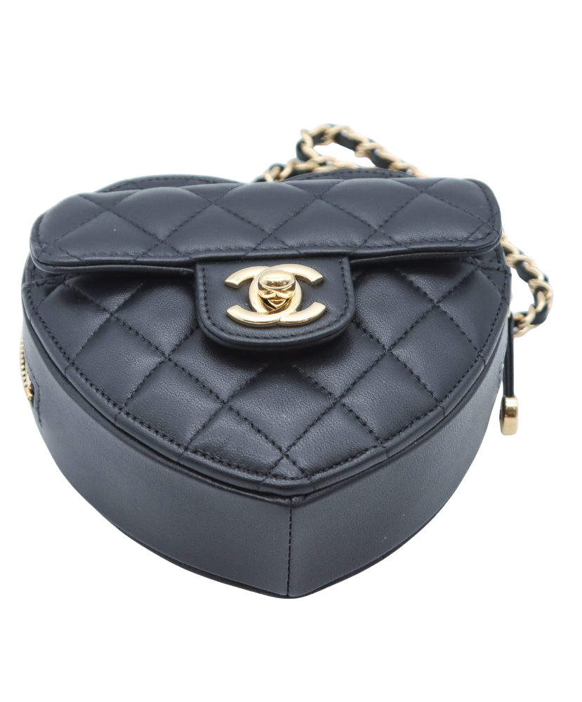Black quilted Chanel heart-shaped handbag with gold chain strap on a white background